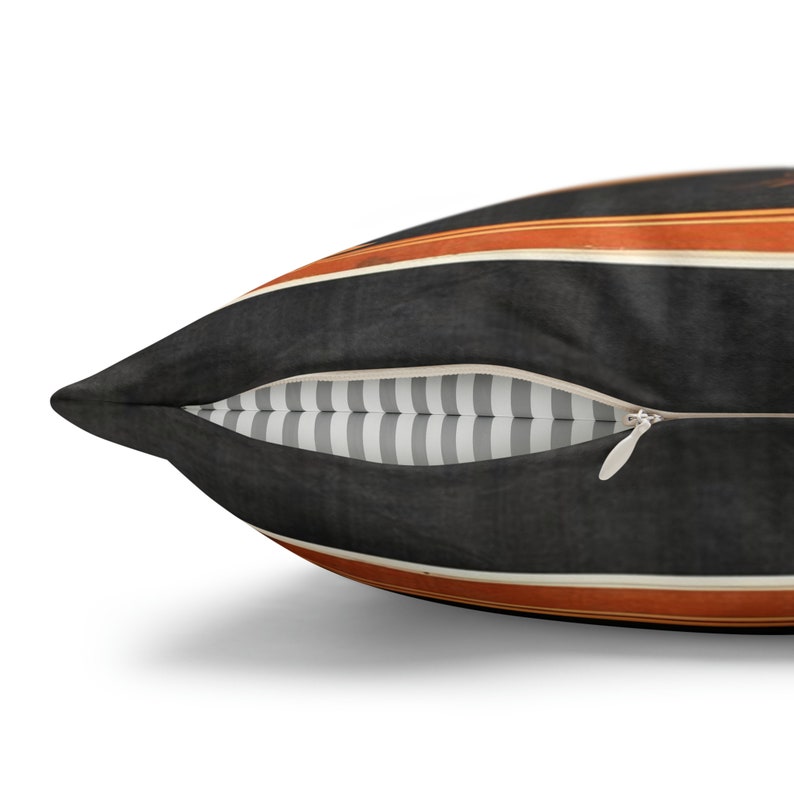 May include: A black and orange striped throw pillow with a zipper closure. The pillow has a white and gray striped lining.