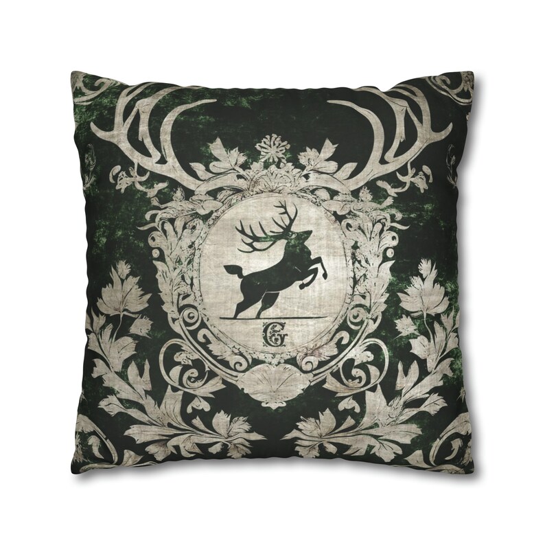 May include: A green and white decorative pillow with a stag silhouette in a crest. The stag is leaping and has large antlers. The crest is surrounded by ornate floral designs.