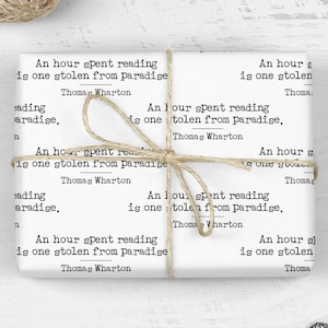 May include: A white gift wrap with a quote from Thomas Wharton: "An hour spent reading is one stolen from paradise." The quote is repeated several times on the wrapping paper.