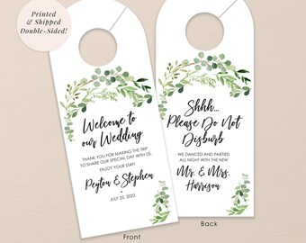 May include: A white wedding door hanger with a green leafy design. The front side says "Welcome to our Wedding" with the names Peyton & Stephen and the date July 25, 2022. The back side says "Shhh... Please Do Not Disturb" with the names Mr. & Mrs. Harrison.