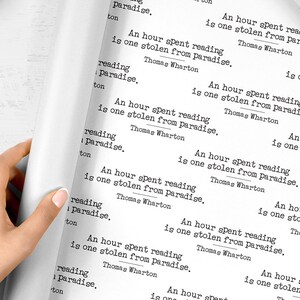 May include: White wrapping paper with a repeating pattern of the quote "An hour spent reading is one stolen from paradise, Thomas Wharton".