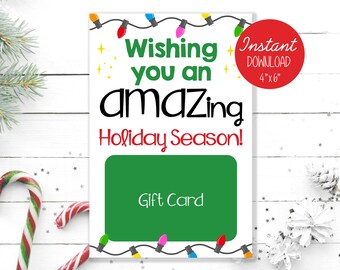 May include: A printable gift card template with a green background and a festive holiday message. The text reads "Wishing you an amazing Holiday Season!" with a string of colorful lights above and below the text. The card is 4 inches by 6 inches.