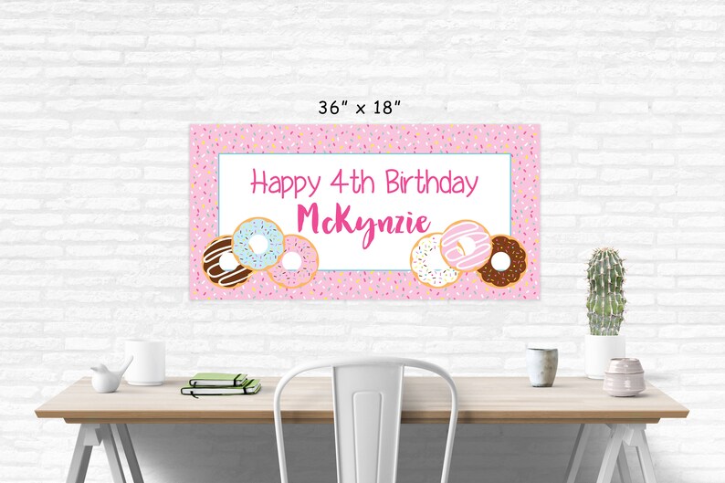 Op de afbeelding: Roze en witte verjaardagsbord met de tekst "Happy 4th Birthday McKenzie" en donut-illustraties. De banner is 91,44 cm bij 45,72 cm.