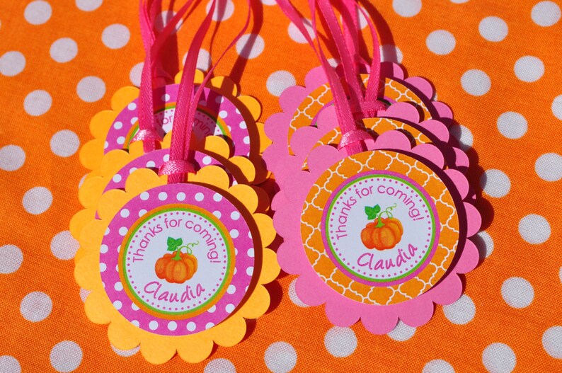 May include: Orange and pink favor tags with scalloped edges. The tags feature a pumpkin design and the text "Thanks for coming! Claudia".