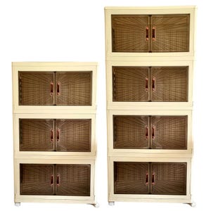 May include: Two cream-colored cabinets with brown, sunburst-patterned doors and copper-colored handles. The cabinets are stacked, with one cabinet having three sections and the other having two sections. The cabinets are on wheels.