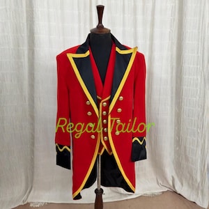 May include: A red tailcoat jacket with black lapels and cuffs, featuring gold-colored buttons and yellow trim. The jacket is displayed on a mannequin and includes the text Regal Tailor in green script across the center of the garment.