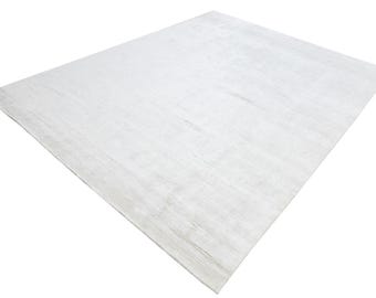 Puede incluir: Una alfombra grande, rectangular, blanquecina con un patrón sutil y texturizado. La superficie de la alfombra tiene un color suave y claro, y las fibras parecen estar tejidas apretadamente. La alfombra es adecuada para salones, dormitorios u otros espacios.