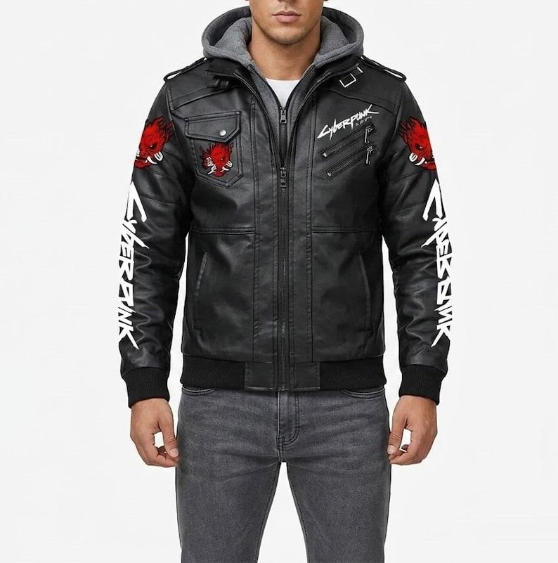K&ouml;nnte beinhalten: Eine schwarze Kunstlederjacke mit grauer Kapuze, verziert mit roten Oni-Masken-Aufn&auml;hern an Schultern und Brust. Die &Auml;rmel und die Brust zeigen wei&szlig;e Cyberpunk-Textgrafiken. Die Jacke verf&uuml;gt &uuml;ber einen Frontrei&szlig;verschluss und Rippb&uuml;ndchen.