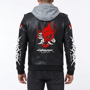 K&ouml;nnte beinhalten: Eine schwarze Kunstlederjacke mit grauem Kapuzeneinsatz. Auf der R&uuml;ckseite befindet sich eine gro&szlig;e rote Grafik einer stilisierten Oni-Maske mit Flammen und dem wei&szlig;en Schriftzug Cyberpunk 2077. Der Schriftzug Cyberpunk 2077 ist vertikal auf den &Auml;rmeln.