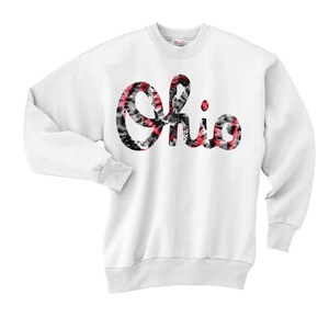 May include: White sweatshirt with a red, black, and white tie-dye design of the word "Ohio".