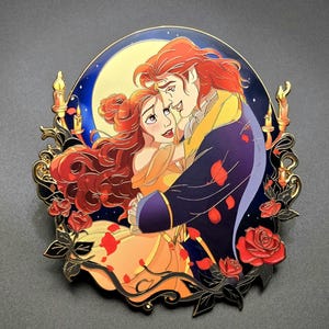 May include: An oval-shaped enamel pin featuring a romantic illustration of a couple dancing. The woman has long brown hair and a yellow dress, while the man has long brown hair and a blue coat. They are framed by red roses and candles.