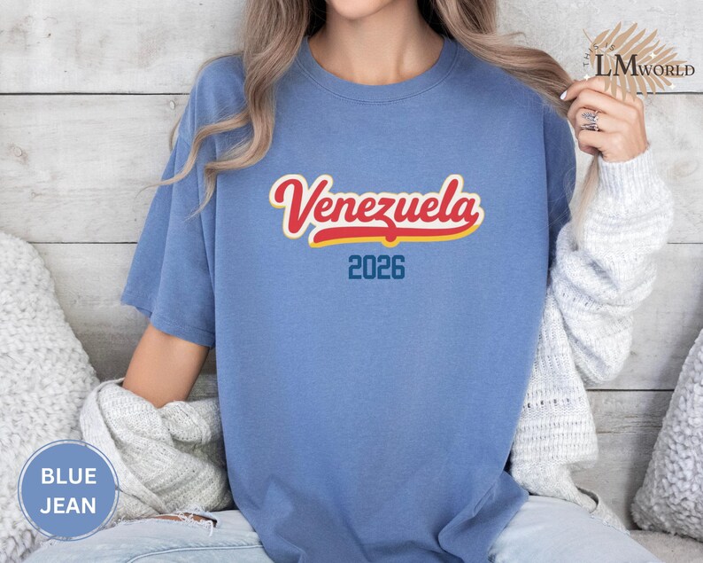 Pu&ograve; includere: Una maglietta blu jeans con la scritta "Venezuela" in rosso e giallo, e l'anno "2026" in blu. La maglietta &egrave; a maniche corte e girocollo.