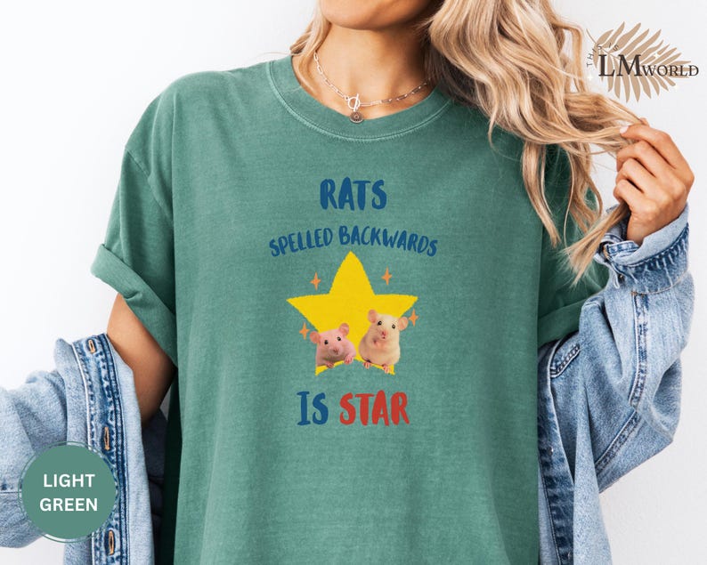 May include: Light green t-shirt with the text "RATS SPELLED BACKWARDS IS STAR" in blue and red. A yellow star with two cartoon rats is in the center. The shirt is a solid color and has rolled-up sleeves.