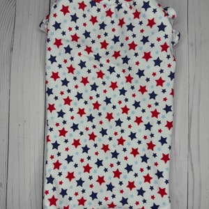 May include: White dog shirt with a red, blue, and white star pattern.