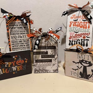 May include: A collection of Halloween-themed decorative signs and tags. The signs feature phrases like "Happy Halloween" and "Time for a Fright." Each piece is adorned with decorative bows in orange, black, and white. The signs have images of pumpkins, bats, and cats.