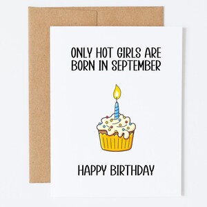 Op de afbeelding: Een witte wenskaart met een bruine envelop met de zwarte tekst ONLY HOT GIRLS ARE BORN IN SEPTEMBER en HAPPY BIRTHDAY, met een centrale illustratie van een gele cupcake met witte glazuur en een enkele brandende blauwe kaars.