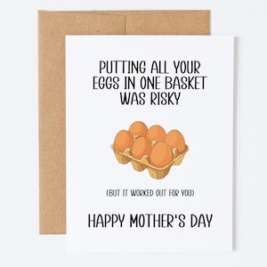 Può includere: Un biglietto bianco con una busta marrone. Il biglietto presenta il testo "PUTTING ALL YOUR EGGS IN ONE BASKET WAS RISKY" e "HAPPY MOTHER'S DAY", con un'illustrazione di uova in un cartone.