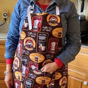 May include: A brown apron with a coffee theme. The apron has a variety of coffee-related images and text, including coffee pots, coffee beans, and the words "Coffee Time".