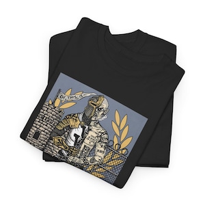 Puede incluir: Camiseta negra con un estampado gráfico de un caballero con casco y un tatuaje en el brazo. El caballero sostiene una bandera que dice "Oh this is..." El gráfico está sobre un fondo azul con una valla y un castillo en el fondo.