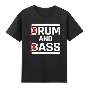 以下が含まれることがあります： 「Drum and Bass」と白文字で書かれた黒いTシャツ。ドラムの文字は線が引かれている。