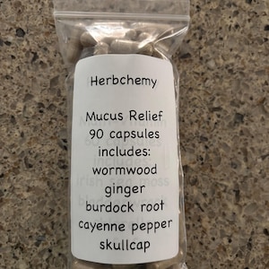Può includere: Un sacchetto di plastica trasparente pieno di capsule. Un'etichetta bianca sulla busta recita "Herbchemy Mucus Relief 90 capsules includes: wormwood, ginger, burdock root, cayenne pepper, skullcap."