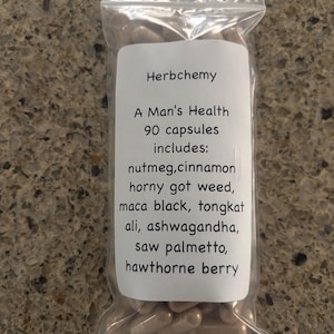 Peut inclure: Un sac en plastique transparent rempli de g&eacute;lules marron. Une &eacute;tiquette blanche sur le sac indique "Herbchemy, A Man's Health, 90 capsules includes: nutmeg, cinnamon, horny got weed, maca black, tongkat ali, ashwagandha, saw palmetto, hawthorne berry."