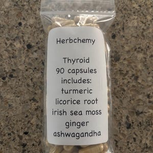 May include: A clear plastic bag filled with beige capsules. A white label on the bag reads "Herbchemy Thyroid 90 capsules includes: turmeric, licorice root, irish sea moss, ginger, ashwagandha."