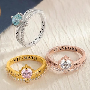 May include: Three personalized rings with gemstones. One silver ring with a blue gemstone and the text "PRINCETON" and "2025". A gold ring with a pink gemstone and the text "LAURA", "MIT-MATH", and "2025". A rose gold ring with a clear gemstone and the text "SHERRY", "STANFORD", and "2025".
