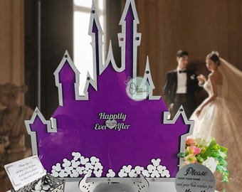 May include: A purple castle-shaped wedding guest book with the text "Happily Ever After." Includes a box for guest notes, pens, and a sign that says "Please leave your name and your best wishes for Mr & Mrs."