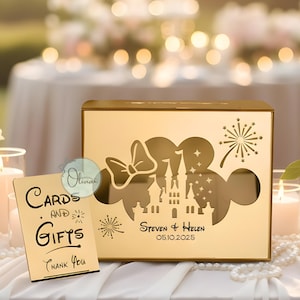 May include: A gold-colored card box with a cut-out design featuring a castle, bow, and fireworks. The box has the names "Steven & Helen" and the date "05.10.2025". A matching sign reads "Cards and Gifts Thank You".
