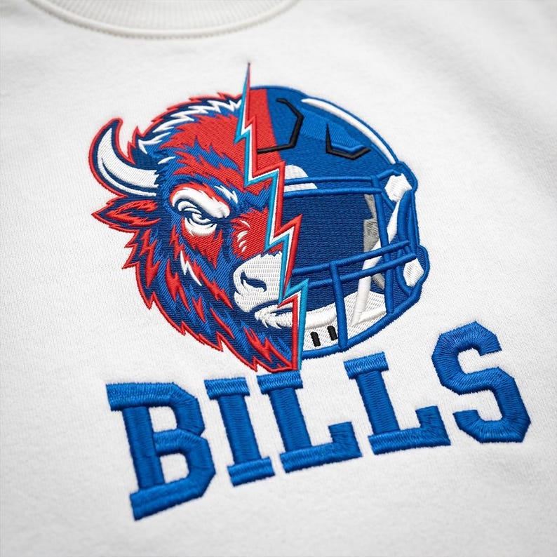 Puede incluir: Una sudadera blanca con un bordado que muestra una cabeza de bisonte dividida por un rayo y un casco de f&uacute;tbol americano. La palabra BILLS est&aacute; bordada en letras azules de bloque debajo del gr&aacute;fico, creando un dise&ntilde;o texturizado y llamativo.