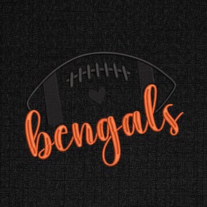 Puede incluir: Un dise&ntilde;o bordado sobre un fondo negro presenta un bal&oacute;n de f&uacute;tbol naranja con la palabra "Bengals" en cursiva. Un peque&ntilde;o coraz&oacute;n negro est&aacute; en el centro del bal&oacute;n.