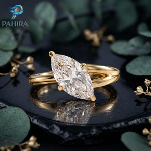 Peut inclure: Une bague en or avec une grande pierre précieuse transparente taille marquise montée sur quatre griffes. L'anneau est en or lisse et poli, présentant une surface réfléchissante. Le design met en valeur la forme allongée de la pierre.