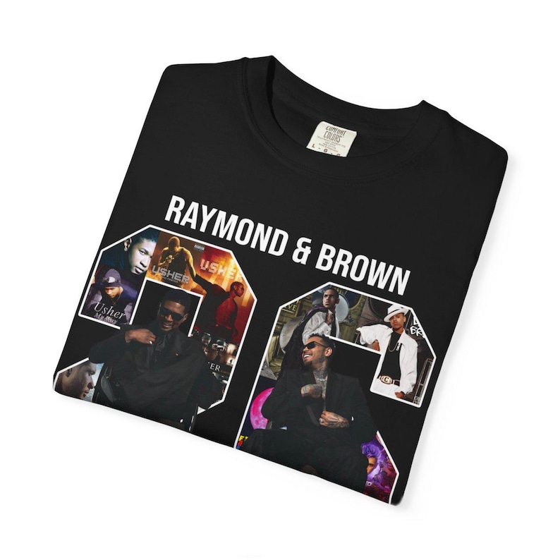 Pu&ograve; includere: T-shirt nero con la scritta bianca "RAYMOND & BROWN". La maglietta presenta un collage di immagini di musicisti. La maglietta &egrave; piegata su una superficie bianca.
