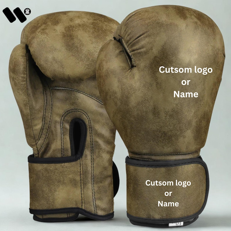 May include: Pair of distressed brown boxing gloves with black accents. The gloves have the text "Cutsom logo or Name" on the wrist and the top of the glove. The gloves are made of a textured material.
