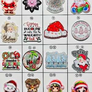 May include: A collection of Christmas-themed charms featuring Santa Claus, snowflakes, reindeer, elves, and festive text. The charms are in various colors, including red, green, white, and gold. Some charms have glitter accents.