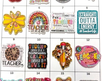 May include: A collection of sixteen colorful acrylic teacher-themed charms arranged in a grid. Each charm features unique designs including apples, pencils, bows, rainbows, and text such as Teacher Life, Teach Them To Be Kind, and Music Teacher.