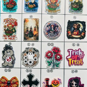 May include: A collection of colorful, glittery acrylic charms featuring various pop culture and Halloween themes. Designs include horror movie characters, cartoon mascots, and Halloween-themed text. Each charm is unique, with vibrant colors and detailed imagery.