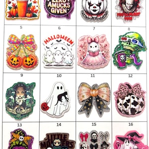 May include: A grid of sixteen decorative acrylic charms featuring Halloween-themed illustrations including pumpkins, ghosts, horror movie characters, and bows. Each charm displays vibrant colors, glitter accents, and text such as Happy Pumpkin Spice Season.