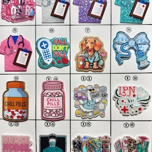 May include: A collection of colorful, glittery acrylic charms and pins with medical themes. Designs include scrubs, stethoscopes, pills, and text like "Medical Goals" and "Nurse Life."