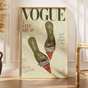Könnte beinhalten: Ein gerahmter Wandkunstdruck, der ein illustriertes Vogue-Magazin-Cover zeigt. Das Design präsentiert zwei olivgrüne Prada-Schuhe mit spitzer orangefarbener Kappe und silbernen Schnallen auf hellem Grund. Der Text umfasst VOGUE, A STEP AHEAD und Good Shoes Brighter Days.
