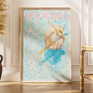Könnte beinhalten: Ein gerahmter Druck eines New Yorker Magazin-Covers mit einer Aquarellillustration einer Person in weißem Badeanzug und Strohhut, die auf einem rosa-weiß gestreiften Schwimmring in blauem Wasser treibt, mit dem Text THE NEW YORKER.
