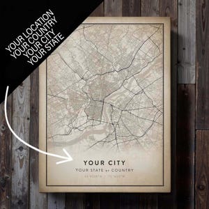 May include: A framed map print with a detailed city map in neutral tones. The text "YOUR CITY" and "YOUR STATE or COUNTRY" is displayed at the bottom, along with coordinates. The top left corner has the text "YOUR LOCATION, YOUR COUNTRY, YOUR CITY, YOUR STATE".