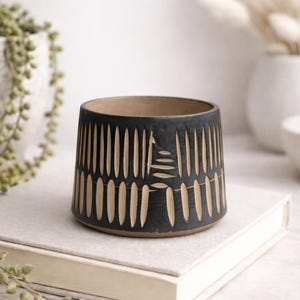 May include: A trio of ceramic mugs with a speckled, matte finish in cream, light grey, and dark grey. Each mug features a simple, modern design and a rounded handle.