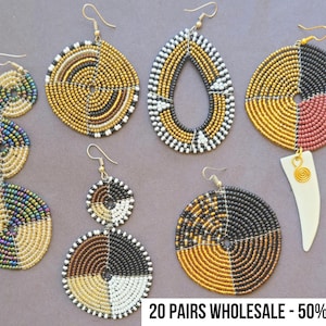 May include: A collection of beaded earrings in various shapes and designs. The earrings feature gold, black, white, and other colorful beads. Some earrings have a circular or teardrop shape. The image includes the text "20 PAIRS WHOLESALE - 50% OFF !!".