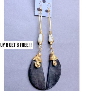 May include: A pair of long, handmade earrings with a gold-tone wire design. The earrings feature a black, crescent-shaped bottom and a white bead. The text "BUY 6 GET 6 FREE !!" is visible.