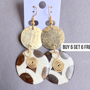 May include: Gold-toned earrings with a hammered disc design and a lower disc with a brown and white pattern. The earrings have a spiral accent and are displayed on a white tag. The text "BUY 6 GET 6 FREE !!" is visible.