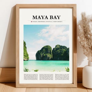 Może przedstawiać: Oprawiony wydruk z napisem "MAYA BAY" nad zdjęciem tropikalnej plaży z turkusową wodą i zielonymi wyspami. Rama wykonana jest z jasnobrązowego drewna.