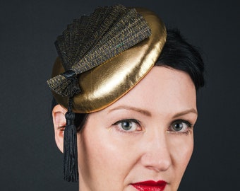 Metallic gold small hat or fascinator with fan decoration and tassel