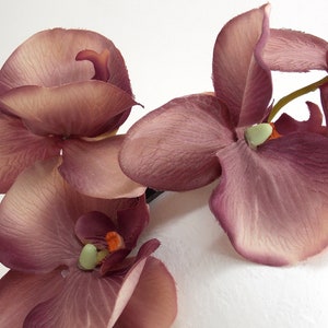 May include: A cluster of mauve silk orchid flowers with green centers. The flowers are arranged in a bouquet and are ready to be used for crafting or decorating.